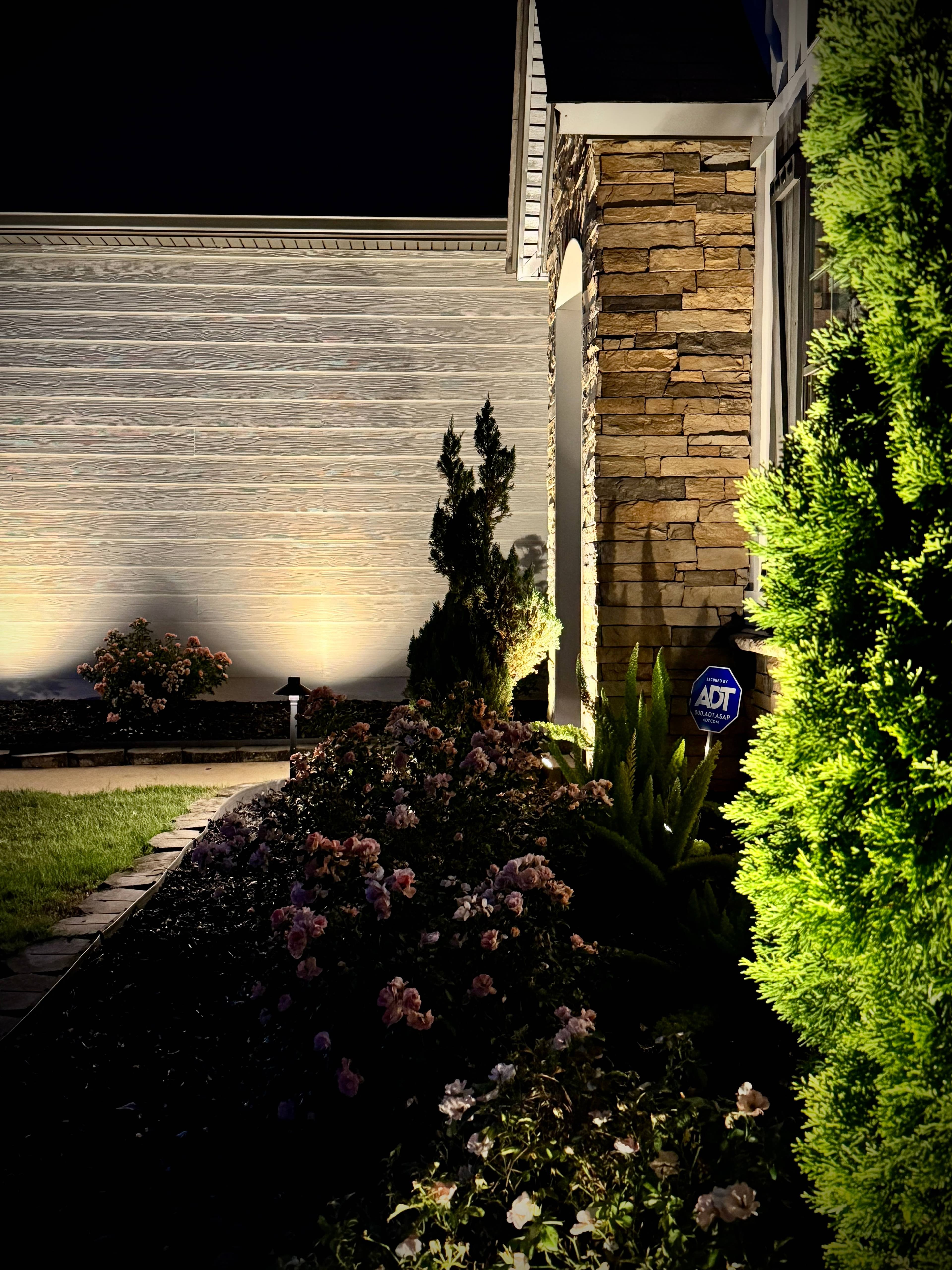 Garage and Entrance Lighting with Stone Column Features Home garage and entrance at night with uplighted stone columns, landscape lighting, and architectural accent lights