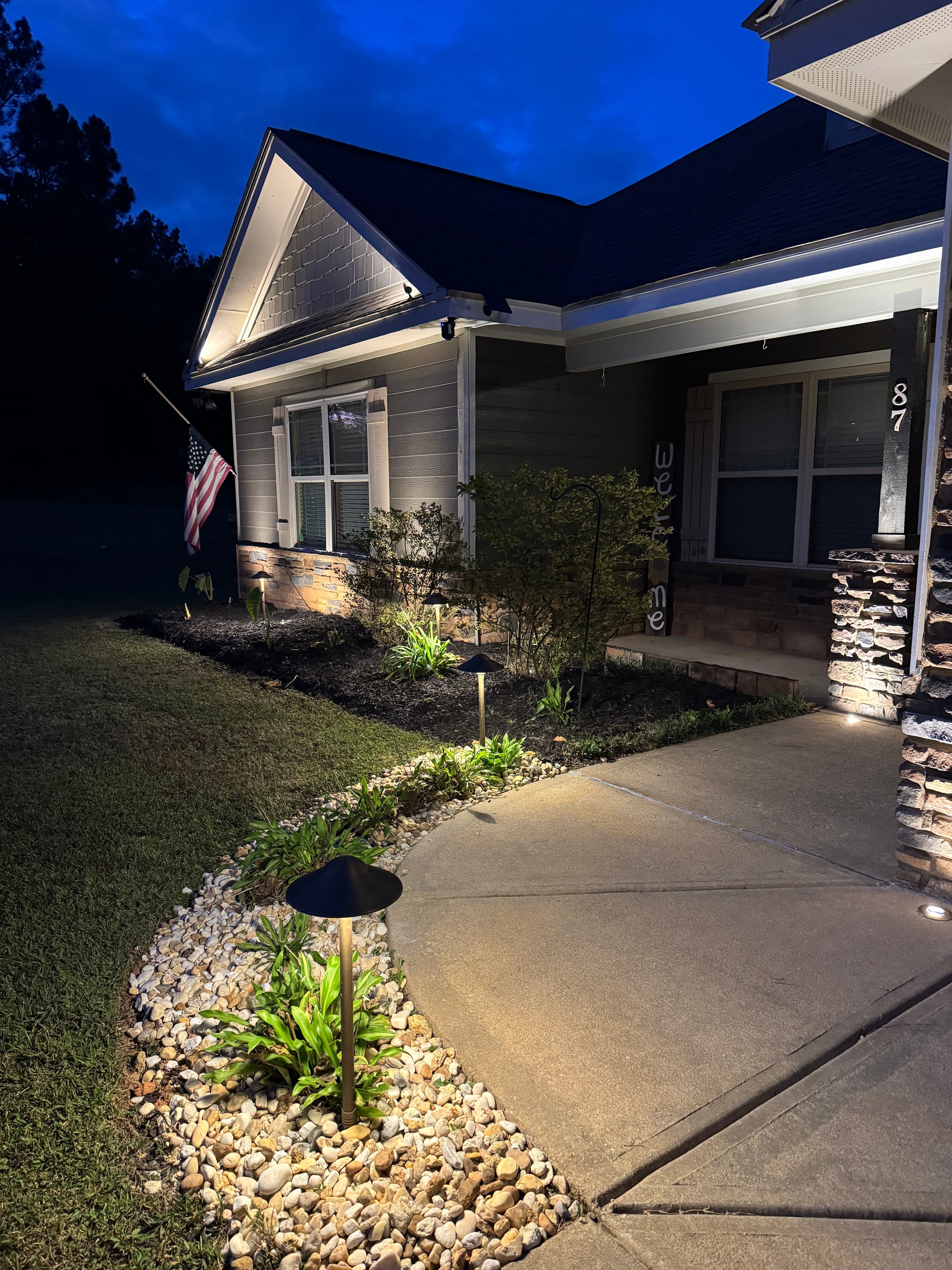 Front Entrance Pathway Lighting Design Home entrance at dusk with illuminated walkway, landscape bed lighting, and architectural facade uplighting