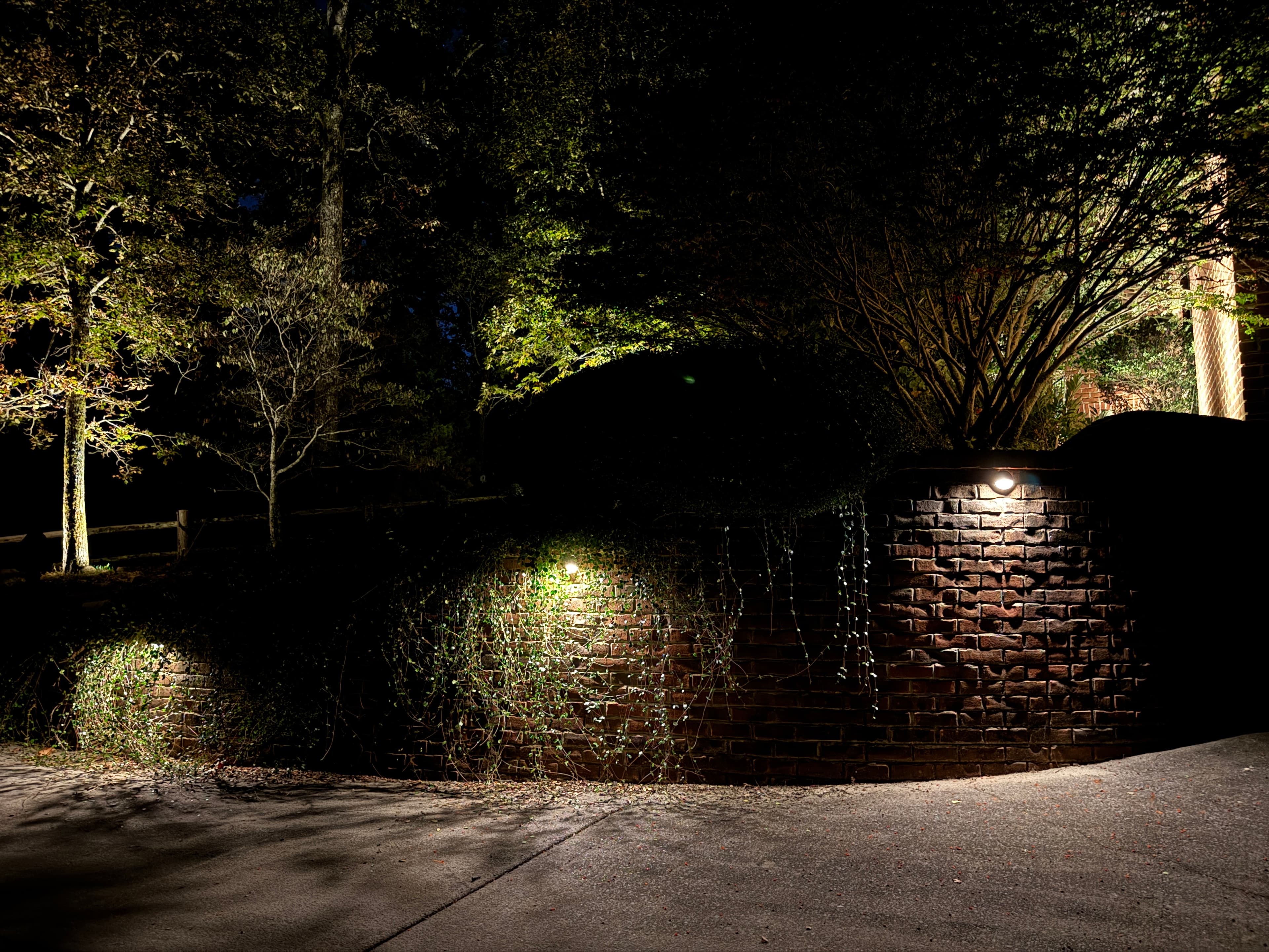 Brick Pillar and Tree Uplighting Installation Brick entrance pillars with uplighting and illuminated trees in background at night