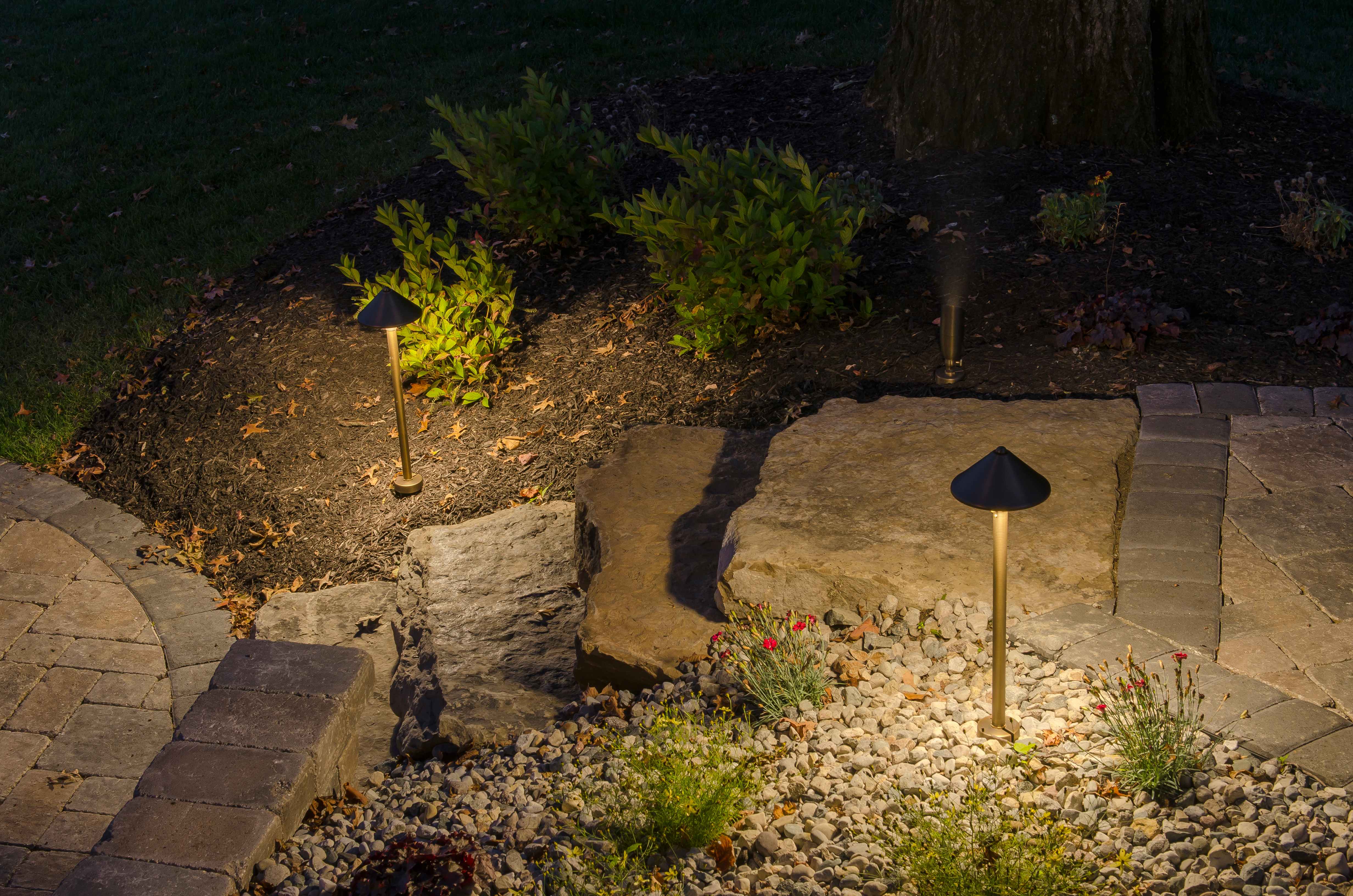 Landscape Boulder and Path Lighting Night shot of brass path lights illuminating landscaping with large boulders, ornamental grasses, and paver pathway in Auburn Alabama